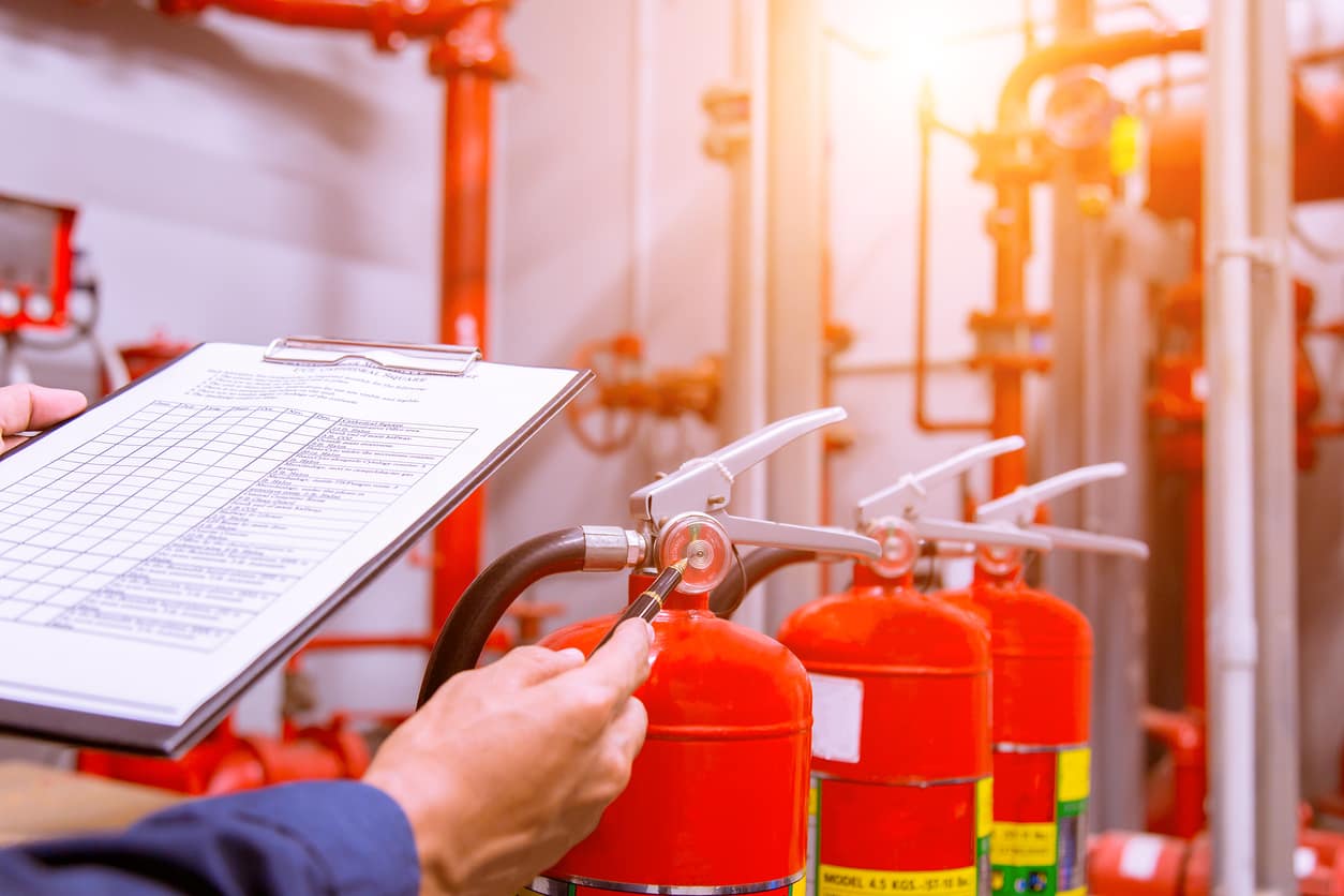 Técnico revisa el manómetro de un extintor con una planilla de inspección